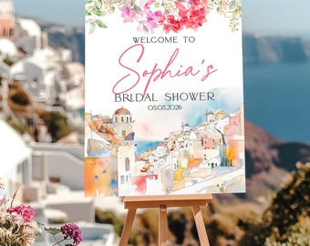 May include: A welcome sign for Sophia's bridal shower, featuring a watercolor painting of a coastal town with white buildings and blue water. The sign is decorated with pink and red flowers and the date 05.05.2026.