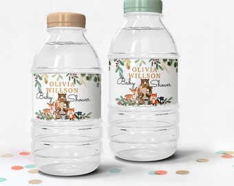 May include: Two clear plastic water bottles with labels that say "Olivia Willson Baby Shower" in gold lettering. The labels feature a watercolor illustration of a bear and other woodland animals.