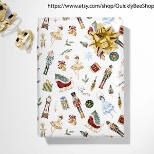 May include: White wrapping paper with a repeating pattern of Christmas-themed illustrations. The illustrations include a nutcracker, a ballerina, a sleigh, a Christmas tree, and a clock. The paper is decorated with gold, red, green, and blue colors.