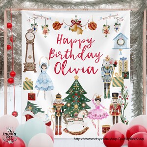 May include: A white backdrop with a winter theme, featuring a Christmas tree, nutcrackers, and ballerinas. The text "Happy Birthday Olivia" is written in red. Decorative elements include ornaments and a clock.
