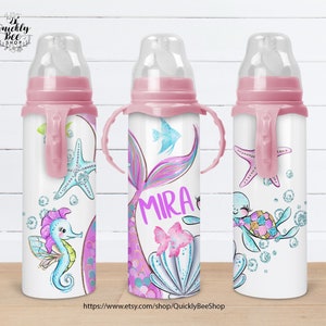Könnte beinhalten: Drei rosa und weiße Babyflaschen mit Meerjungfrauen-, Seestern- und Schildkrötenmotiven. Die Flaschen haben Griffe und sind mit Glitzer und Pastellfarben verziert. Die mittlere Flasche trägt den Namen "MIRA".