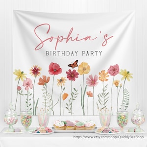May include: A white fabric backdrop featuring a watercolor illustration of colorful wildflowers and a monarch butterfly. The text "Sophia's BIRTHDAY PARTY" is printed in pink and black lettering. The banner is displayed above a table with sweets.