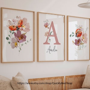 May include: Three framed prints with a floral design featuring ladybugs and the letter A with the name Amelia. The prints have a white background with pink and green floral accents.