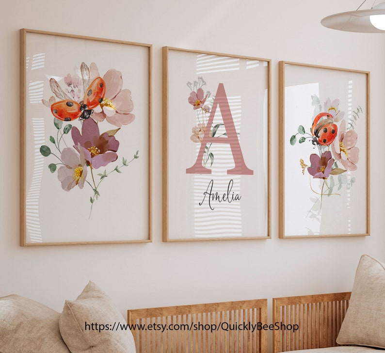 May include: Three framed prints with a floral design featuring ladybugs and the letter A with the name Amelia. The prints have a white background with pink and green floral accents.
