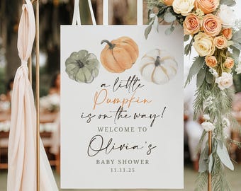 May include: A white sign with watercolour pumpkins and the text "a little pumpkin is on the way!" announces Olivia's baby shower. The sign is decorated with flowers and ribbons.