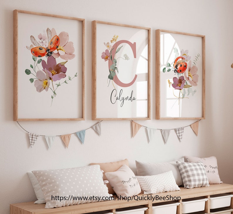 May include: Three framed prints with watercolor floral designs and ladybugs. The middle print features a pink letter C with the name "Calynda" written below.