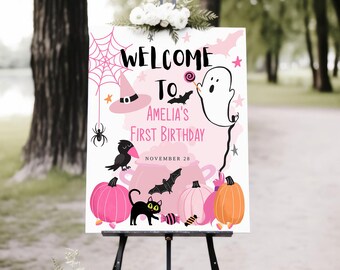 May include: Pink and black Halloween welcome sign with a ghost, bats, a cauldron, pumpkins, and a black cat. The sign says "Welcome to Amelia's First Birthday, November 28".