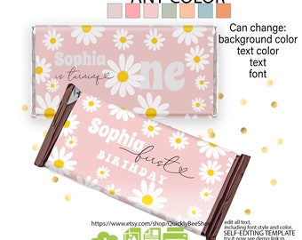 Op de afbeelding: Roze chocoladereepverpakking met witte madeliefjes en de tekst "Sophia is turning one". Het verpakkingsontwerp bevat de tekst "Sophia first birthday". De verpakking is een zelfbewerkbare sjabloon.