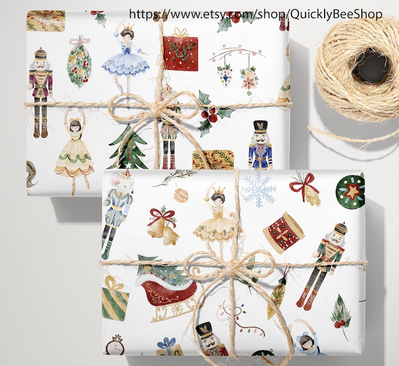 May include: Two sheets of white wrapping paper with a repeating pattern of nutcracker soldiers, ballerinas, Christmas trees, and other holiday decorations. The paper is tied with twine.