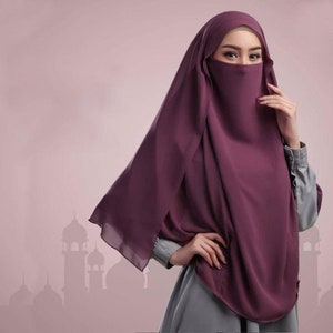 May include: A plum-coloured niqab, a veil that covers the face, with a matching head covering. The fabric drapes over the shoulders and chest. The background is a soft pink with a silhouette of a mosque.