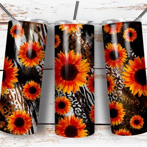 May include: Three stainless steel tumblers with a black, white, and brown animal print background. The tumblers are decorated with orange and yellow sunflowers.