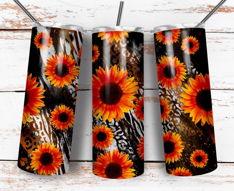 May include: Three stainless steel tumblers with a black, white, and brown animal print background. The tumblers are decorated with orange and yellow sunflowers.