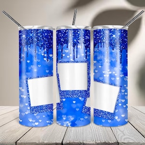May include: Three cylindrical tumblers with a blue glitter drip pattern at the top, featuring a blue background with white heart shapes and blank white photo frame graphics. Each tumbler includes a thin metal straw inserted into the lid.