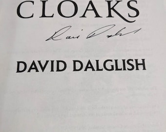 May include: A white book cover with the title "A Dance of Cloaks" in black text. The author's name, "David Dalglish", is printed below the title. The book cover also features a black and white logo for "Orbit" at the bottom.