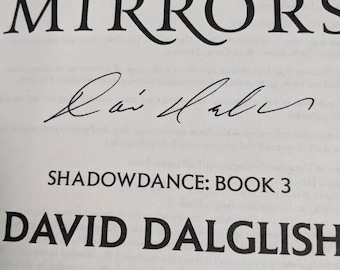 May include: Close-up of a book cover with the title "A Dance of Mirrors" in large, black, stylized font. Below the title is a signature, followed by "Shadowdance: Book 3" and the author's name, David Dalglish.