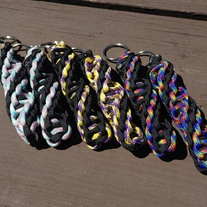 May include: Five colorful paracord keychains with black accents. Each keychain has a silver metal ring.