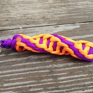 May include: A purple and orange braided key chain with a silver key ring.