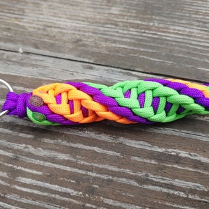 May include: A green, purple, and orange braided paracord keychain with a silver key ring.