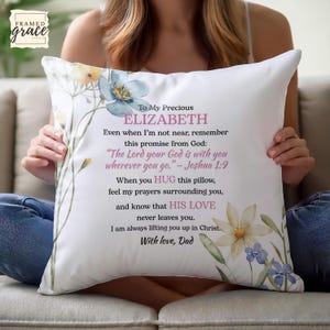 Op de afbeelding: Wit decoratief kussen met bloemenaccenten en tekst. Het kussen heeft een aquarelontwerp van bloemen in geel, blauw en roze. De tekst bevat een persoonlijke boodschap aan Elizabeth van Dad.
