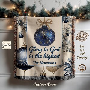 Può includere: Un arazzo beige con un design di ornamento natalizio. L'arazzo presenta un grande ornamento blu con fiocchi di neve, il testo "Glory to God in the highest" e il nome "The Newmans". È realizzato in 100% cotone.