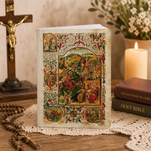 Puede incluir: Un libro de tapa dura con una cubierta ornamentada y colorida que presenta ilustraciones religiosas y bordes decorativos. El libro está abierto, revelando páginas blancas. Un crucifijo de madera, un rosario y otros libros están en el fondo.