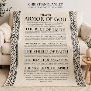 May include: Cream Christian blanket with black text detailing the Armor of God prayer. The blanket has a decorative border and is made of sherpa or velveeteen. The text includes Ephesians 6:10-18.