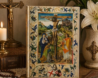 Pode incluir: Um livro de capa dura com uma pintura religiosa na capa, retratando a crucificação de Jesus. A capa tem uma borda ornamentada com desenhos florais e de rolagem. Um crucifixo dourado, uma vela acesa e um vaso de lírios brancos estão no fundo.