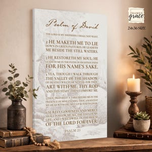 Puede incluir: Un lienzo rectangular para pared que presenta el texto del Salmo 23 en letras marrones sobre un fondo claro con una ilustraci&oacute;n tenue de ovejas. El texto incluye el t&iacute;tulo Salmo de David y los vers&iacute;culos del 1 al 6. El lienzo indica tama&ntilde;o 24x36.