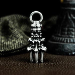 May include: A silver pendant with a detailed, intricate design. The pendant is shaped like a tower with a pointed top and a loop at the top for attaching a chain.