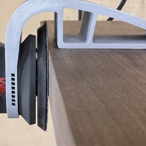 May include: A gray 3D printed sanding jig with a sanding pad attached to a power sander. The jig is designed to help sand edges and curves.