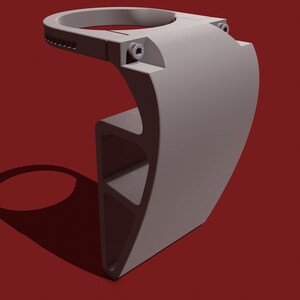 May include: A gray 3D printed phone holder with a circular top and a curved base. The holder has a textured surface and a small hole on the side.