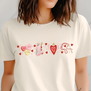 May include: A white t-shirt with a red, pink and white graphic design featuring a saint, hearts and the text "St. Valentine's Love".