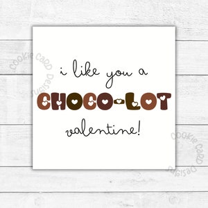 May include: A white card with black text that reads "i like you a choco-lot valentine!" The word "choco-lot" is in brown letters with white hearts.