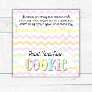 May include: A pastel pink, yellow and blue chevron patterned card with the text "Paint Your Own Cookie" in a white cloud with a colourful outline. The text is in a playful font.