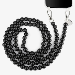 Può includere: Un cinturino per telefono nero con perline e chiusura argentata. Il cinturino è fatto di perline rotonde nere ed è abbastanza lungo da indossare intorno al collo.