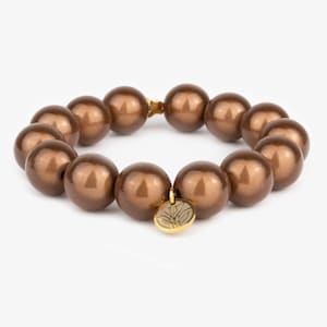 Könnte beinhalten: Ein braunes Perlenarmband mit einem goldenen Anhänger. Die Perlen sind groß und rund, und der Anhänger hat ein Blattdesign.
