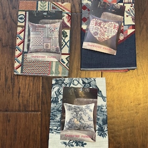 Peut inclure: Trois panneaux de tapisserie avec des images de coussins décoratifs. Les panneaux présentent divers motifs et couleurs, notamment des patchworks, des motifs floraux et des toiles de Jouy. Chaque panneau porte l'étiquette "TAPESTRY PANEL".