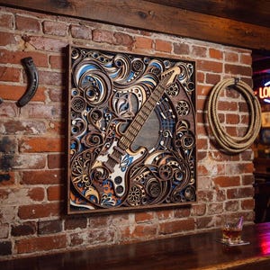 May include: A detailed wooden wall art piece featuring a guitar design with intricate layered patterns in shades of brown, blue, and orange. The artwork is mounted on a brick wall, with a horseshoe and rope decor nearby.