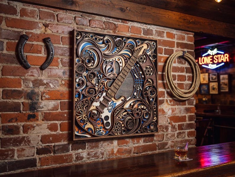 May include: A detailed wooden wall art piece featuring a guitar design with intricate layered patterns in shades of brown, blue, and orange. The artwork is mounted on a brick wall, with a horseshoe and rope decor nearby.
