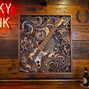 May include: A wooden, layered art piece featuring a guitar design with intricate details in shades of brown, blue, and white. The artwork is mounted on a wooden wall, with a neon "ONKY TONK" sign visible. A beer bottle sits on a wooden bar.
