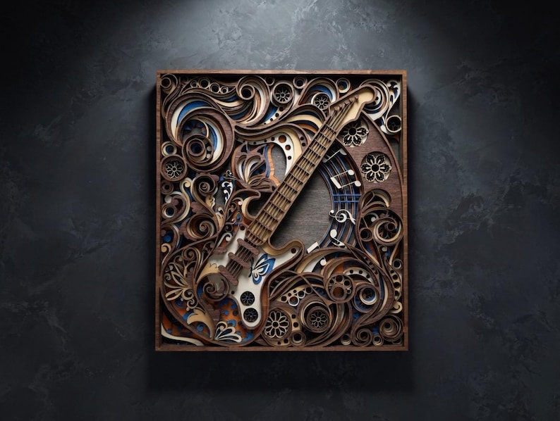 May include: A layered wooden art piece featuring a detailed electric guitar design. The artwork incorporates swirling patterns, floral elements, and musical notes in shades of brown, blue, and white, all within a square frame.