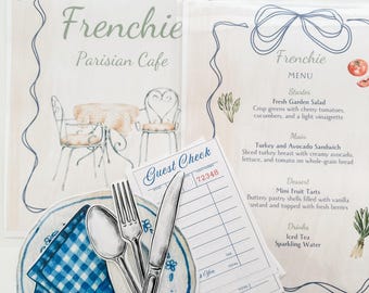 Könnte beinhalten: Eine Aquarell-Illustration einer Pariser Café-Speisekarte mit einem Gast-Check, einem Teller mit einer blau-weiß karierten Serviette, einer Gabel, einem Messer und einem Löffel. Die Speisekarte bietet Gerichte wie frischen Gartensalat, Truthahn-Avocado-Sandwich, Mini-Fruchttörtchen, Eistee und Mineralwasser.