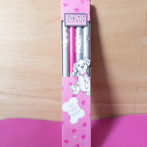 May include: A pack of three pink and silver book covers featuring a Dalmatian puppy design. The covers are from The Disney Store and say "101 Dalmatians" on the front. The pack says "Book Covers - Couvertures de Livres - Cubiertas para Libros".