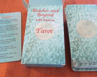 May include: A turquoise blue box with the text "Beaches and Beyond with Melissa Tarot" on the front. The box contains a deck of tarot cards with a turquoise blue and white design.