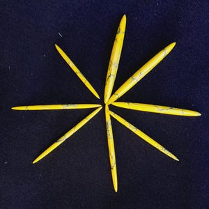 May include: Eight yellow, marbled, pointed, decorative pieces arranged in a star shape on a dark blue background.