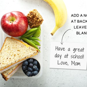 May include: A packed lunch in a clear container with a sandwich, apple, blueberries, snap peas, and a banana. A note says "Have a great day at school! Love, Mom."