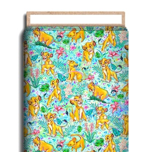 May include: A blue and green fabric with a repeating pattern of cartoon lion cubs. The cubs are in various poses, some are walking, some are sitting, and some are standing. The fabric is perfect for crafting projects, quilting, and making clothing.