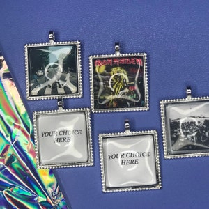 May include: Five silver-framed square pendants with glass inserts. The pendants feature images of a crosswalk, a band, a crowd, and two blank spaces that say "Your Choice Here".