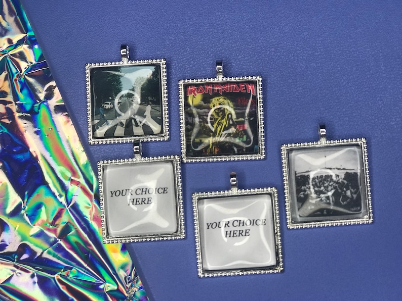 May include: Five silver-framed square pendants with glass inserts. The pendants feature images of a crosswalk, a band, a crowd, and two blank spaces that say "Your Choice Here".