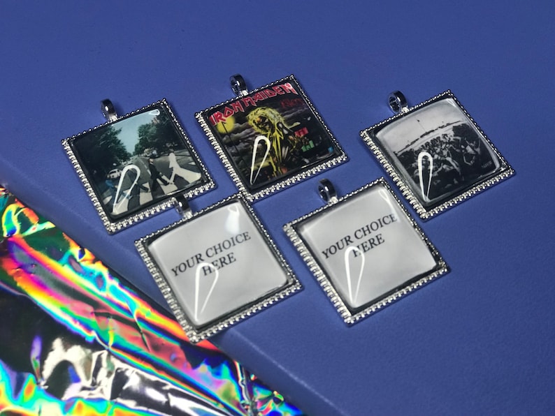 May include: Five silver-framed square pendants with different images. The images include a band, a crosswalk, and a crowd. Two pendants have the text "Your Choice Here".